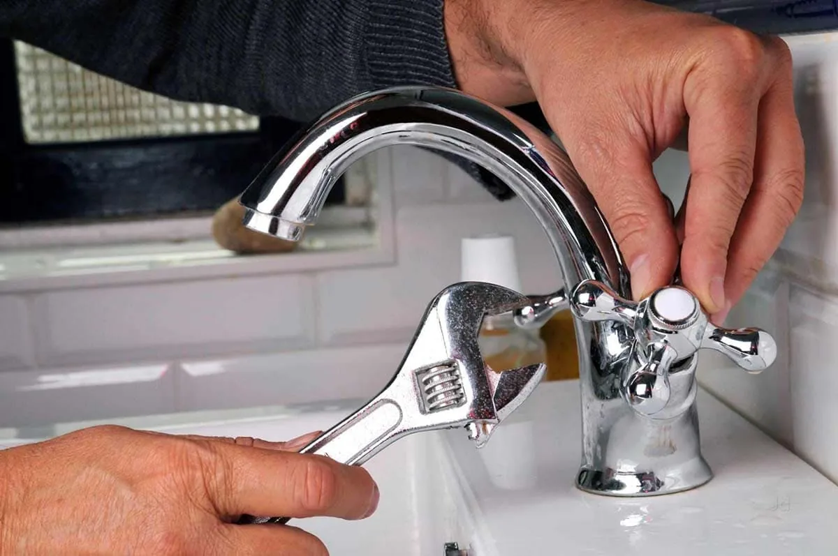 Fontanero cambiando la grifería de un lavabo en una vivienda de Tenerife