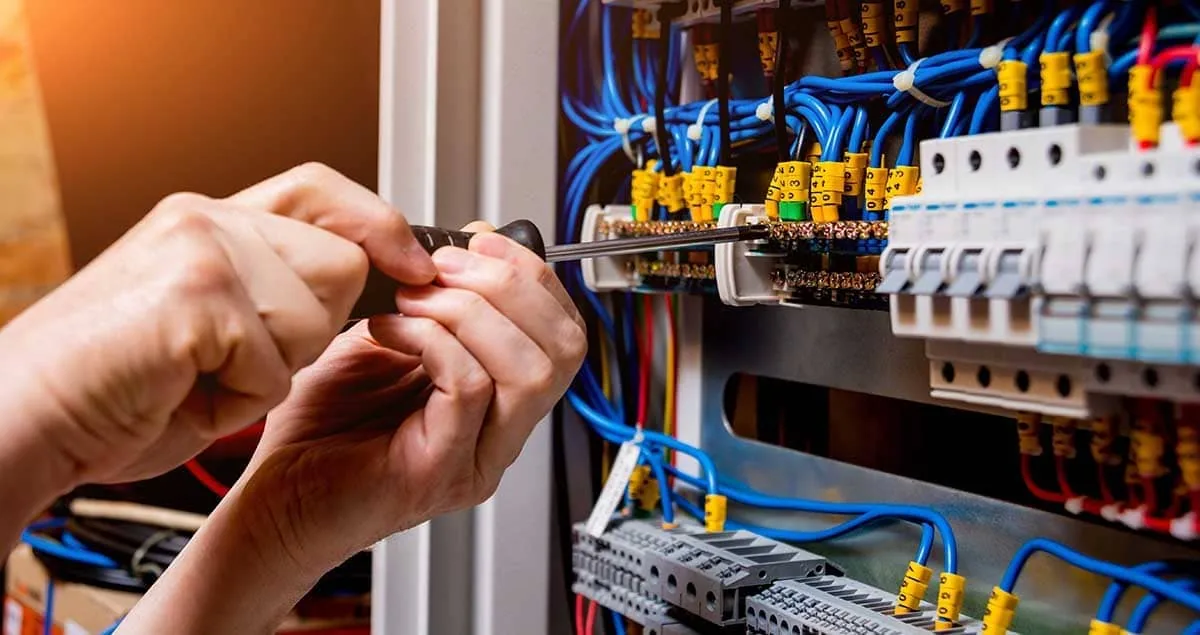 Instalador autorizado revisando y apretando conexiones en un cuadro eléctrico en Tenerife