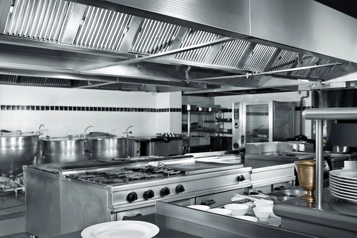 Campana industrial de lamas de acero inoxidable sobre fogones y plancha en la cocina de un restaurante de la costa de Mallorca
