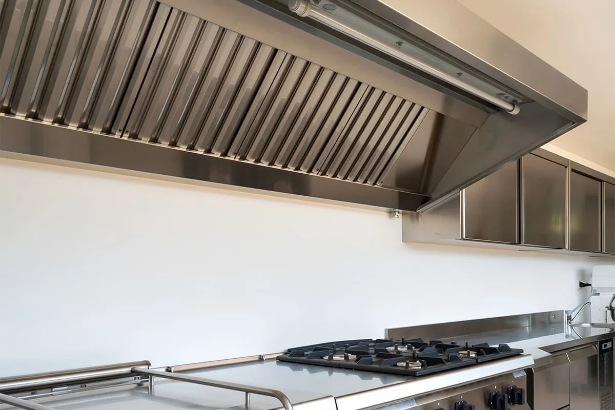 Campana mural de hostelería con filtros de lamas sobre una cocina de gas en un local de Madrid