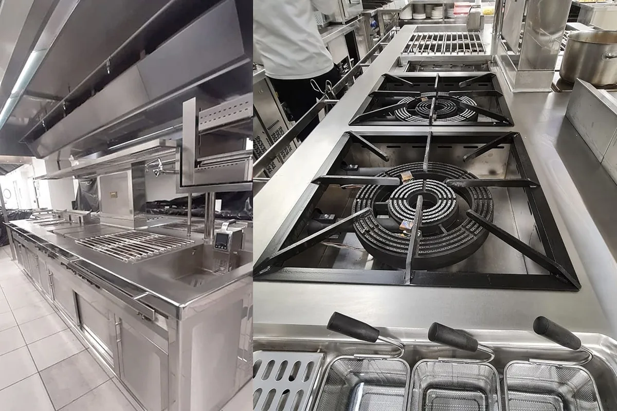 Cocina profesional de acero inoxidable con campana, fogones de gran diámetro con parrillas negras y freidoras con cestillas, en un local de hostelería de Granada