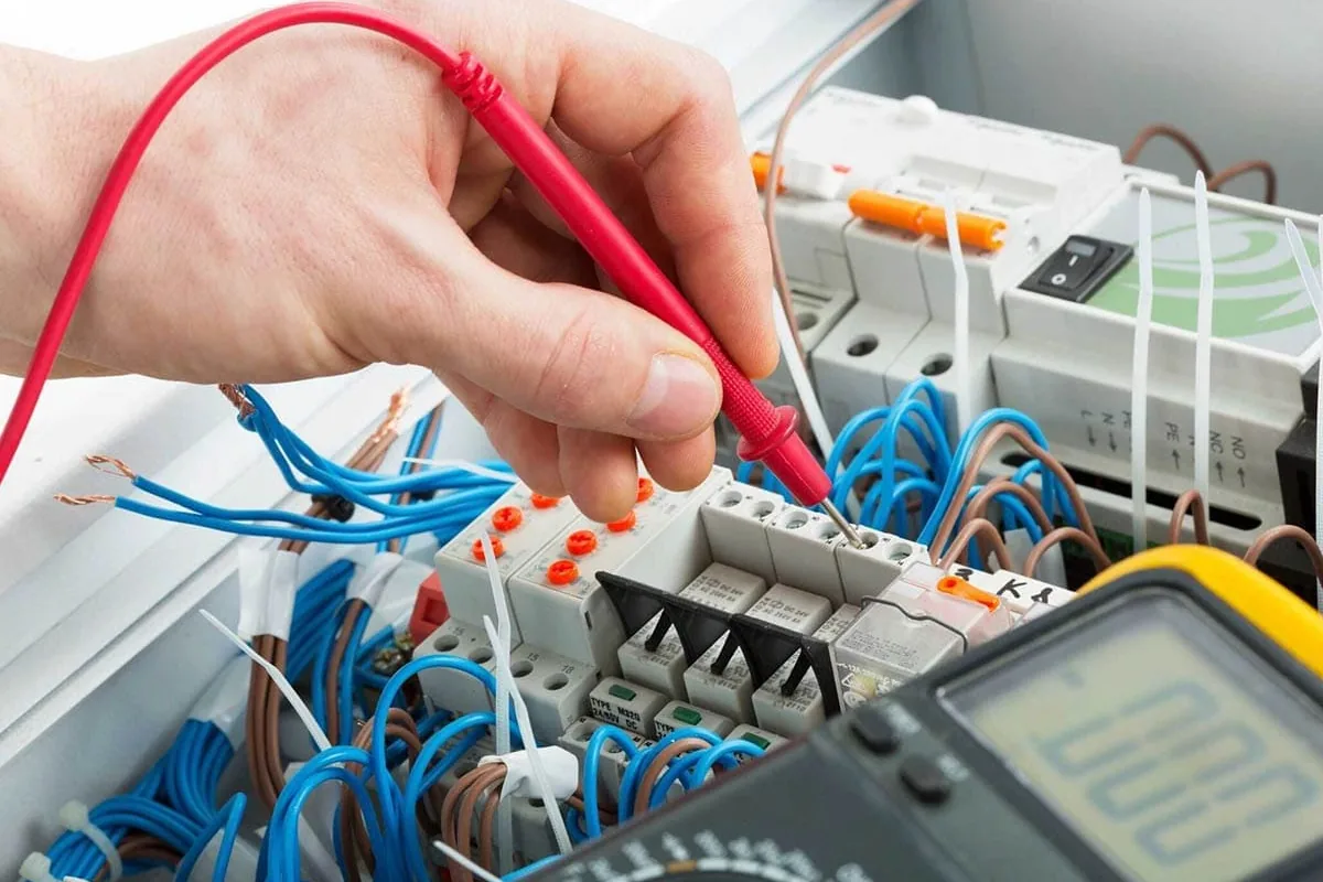 Mano con la punta de un polímetro comprobando una regleta de bornas dentro de un cuadro eléctrico de una vivienda de Elche