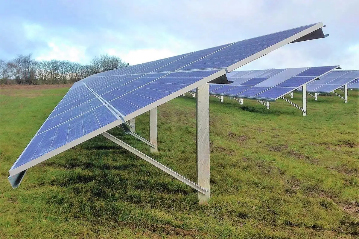 Estructura de acero galvanizado que sujeta filas de paneles solares sobre un prado bajo un cielo con nubes, el tipo de montaje que se estudia para A Coruña