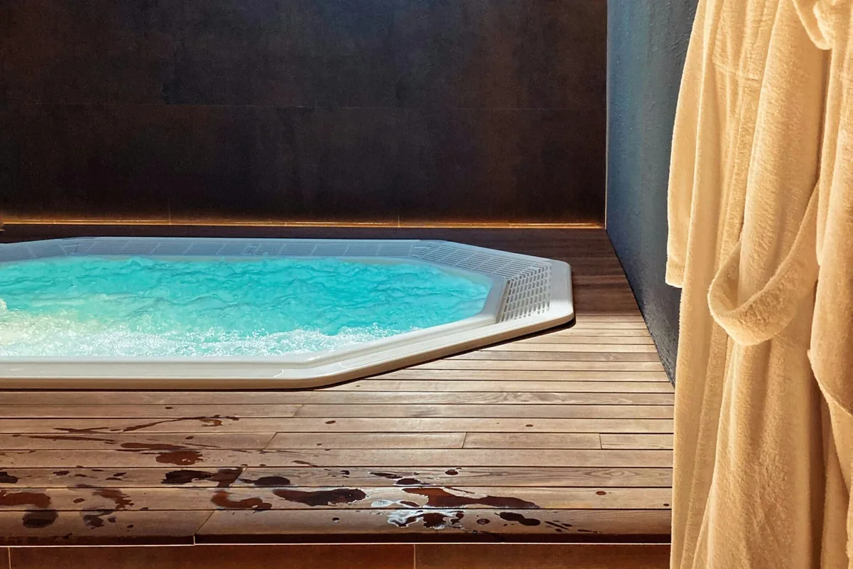 Spa de obra octogonal encastrado en una tarima de madera bajo un lucernario, en un ático de Palma