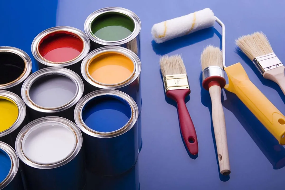 Botes abiertos de pintura de varios colores con brochas y rodillo preparados para un trabajo en Barcelona