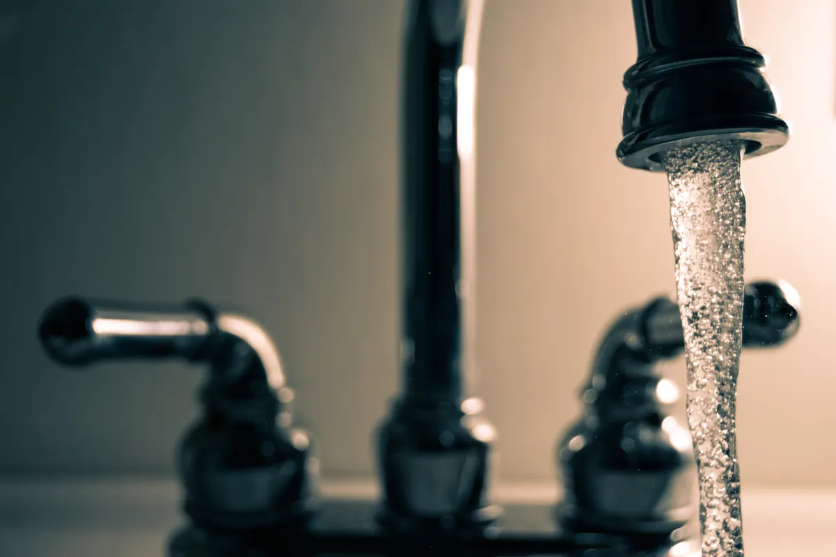 Agua saliendo de un grifo de acero en un plano detallado