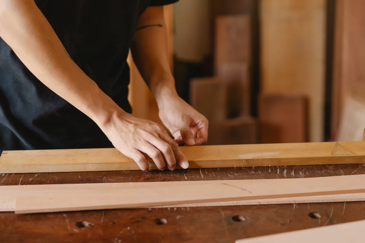 Artesano trabajando con tablones de madera en un taller de carpintería durante el día