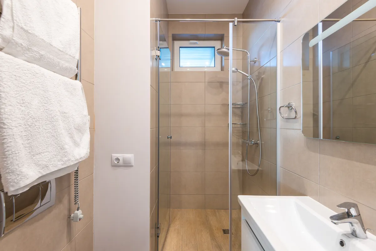 Baño contemporáneo con mampara de cristal y azulejos beis