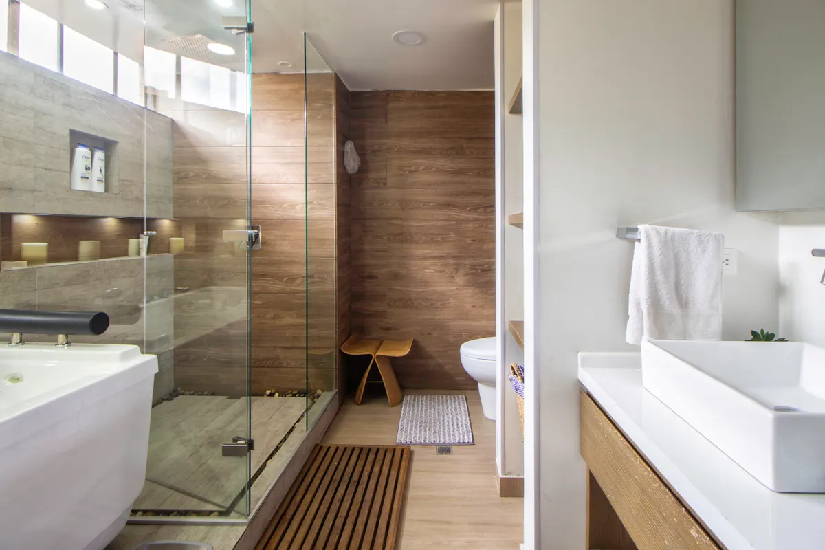 Baño moderno con ducha de cristal, detalles de madera y lavabo de diseño