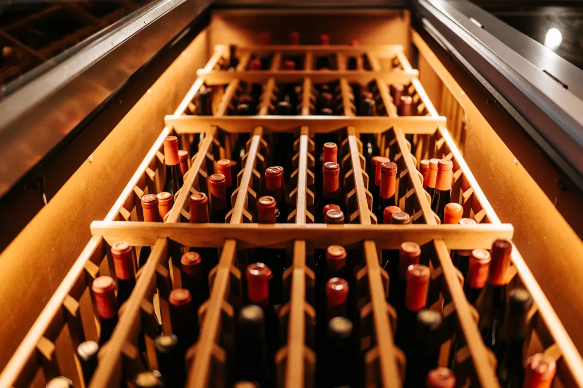 Botellas de vino guardadas en un botellero de madera con tonos cálidos