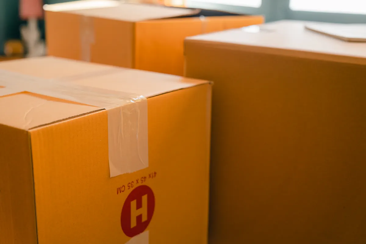 Cajas de cartón precintadas para una mudanza junto a una ventana en un día soleado