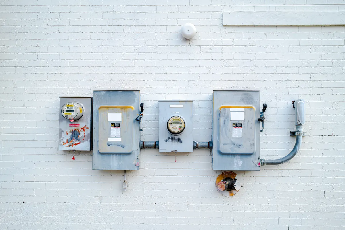 Cajas eléctricas y contadores de luz instalados en una pared de ladrillo blanco