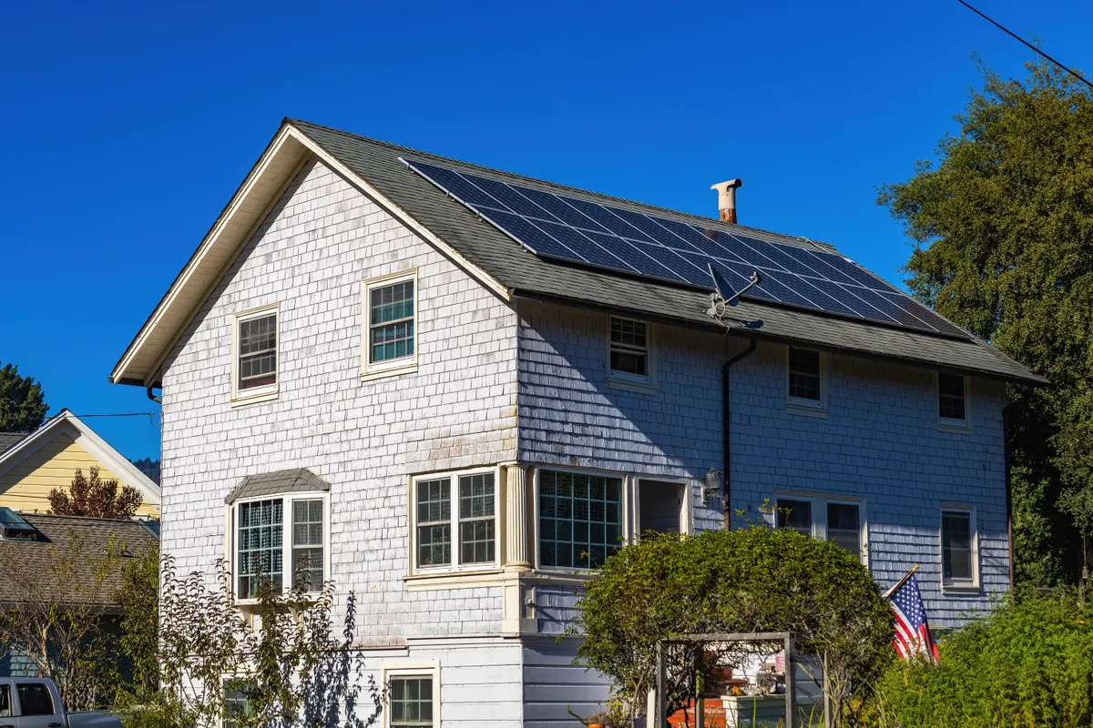 Casa moderna de dos plantas con placas solares en el tejado y cielo despejado