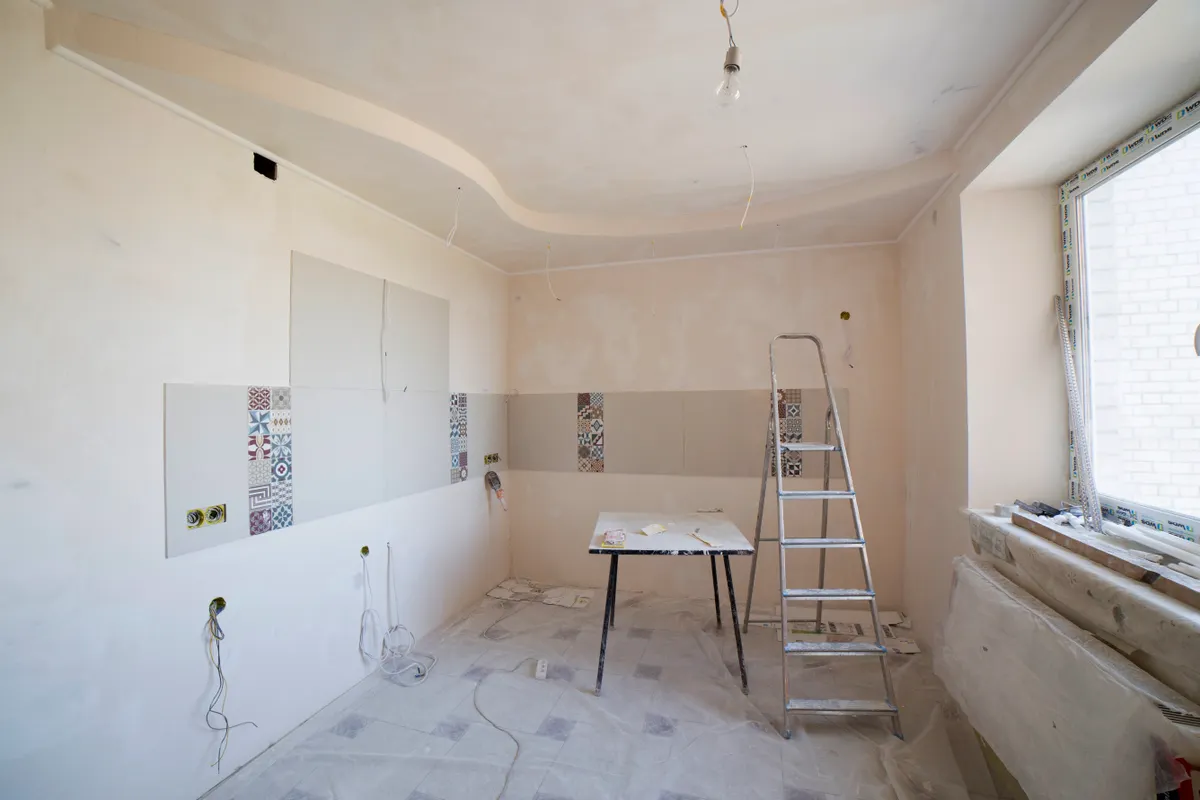 Cocina amplia en plena reforma con una escalera y herramientas
