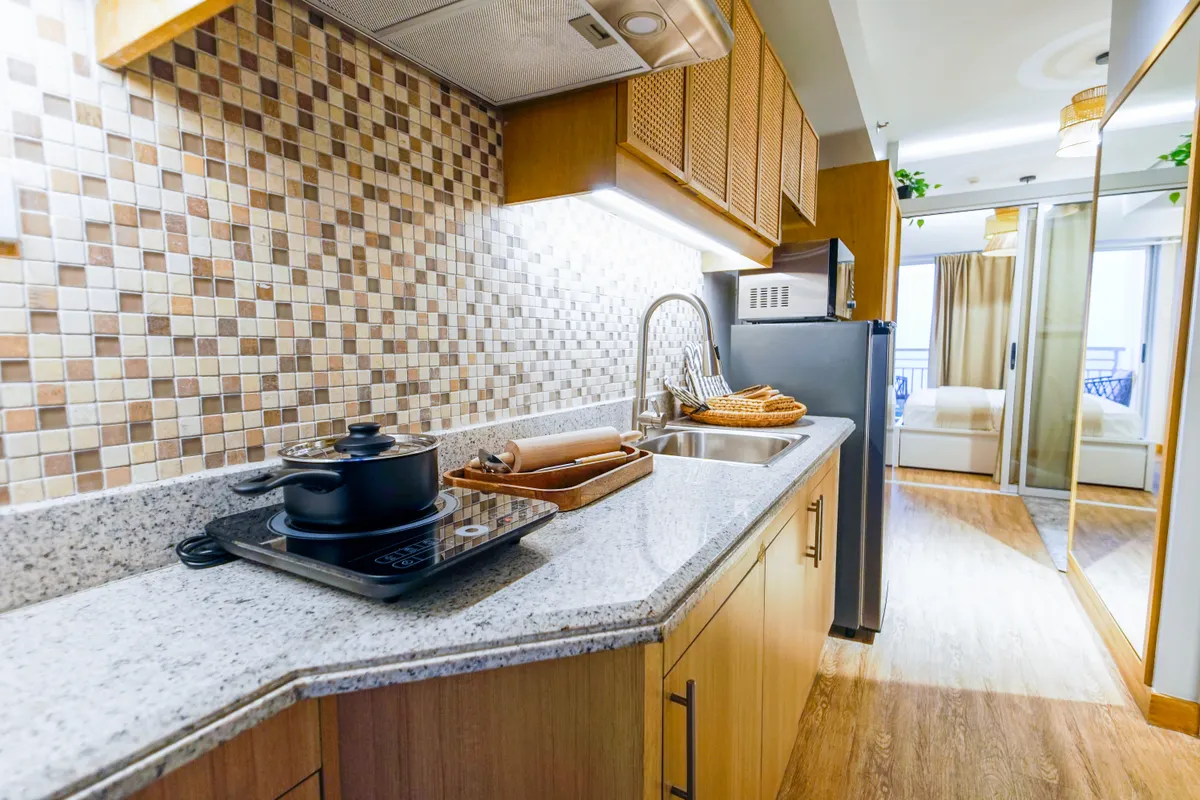 Cocina amplia y moderna con placa de inducción, encimera de granito y muebles de madera