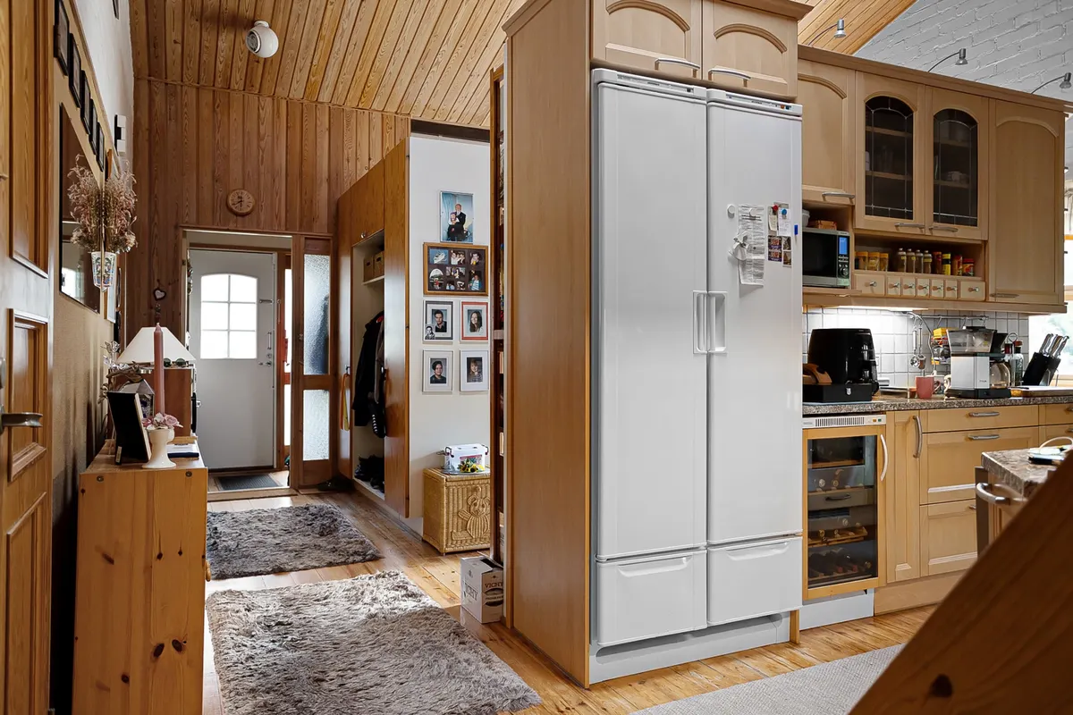 Cocina de madera con un frigorífico blanco de dos puertas y una vinoteca integrada bajo la encimera