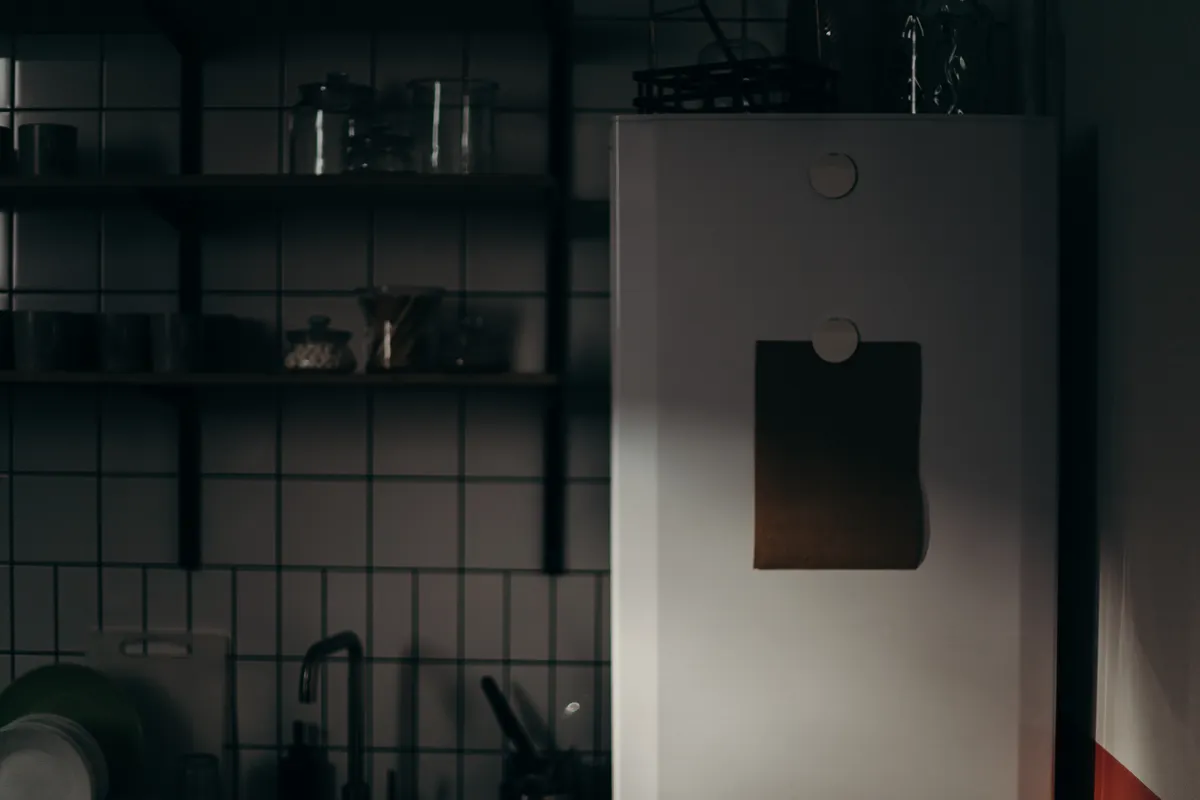 Cocina en penumbra con un frigorífico y estantes de líneas sencillas
