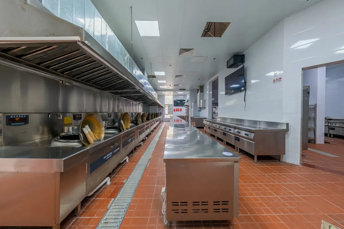 Cocina industrial de acero inoxidable, limpia y sin gente, con suelo de baldosa