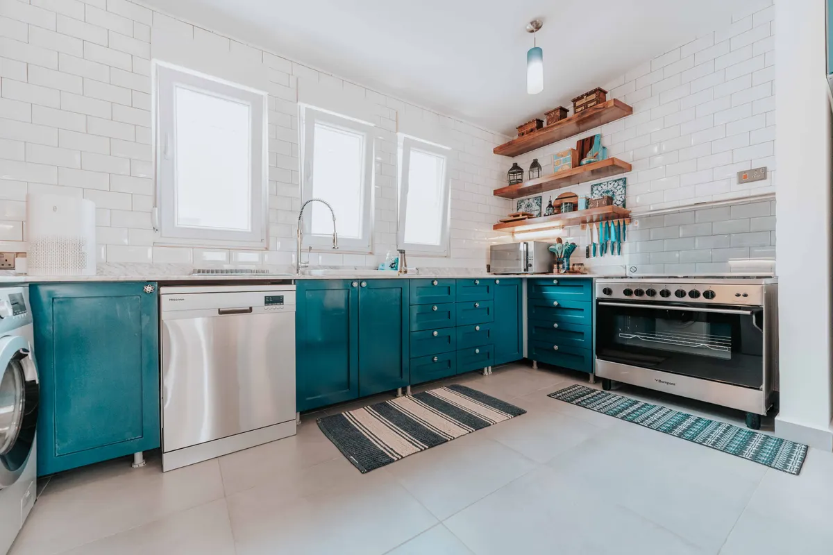 Cocina luminosa con muebles azules, electrodomésticos de acero y estantes abiertos