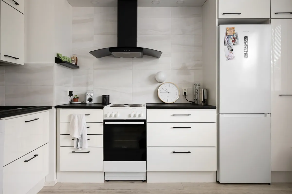 Cocina minimalista con muebles blancos, placa de cocina y frigorífico