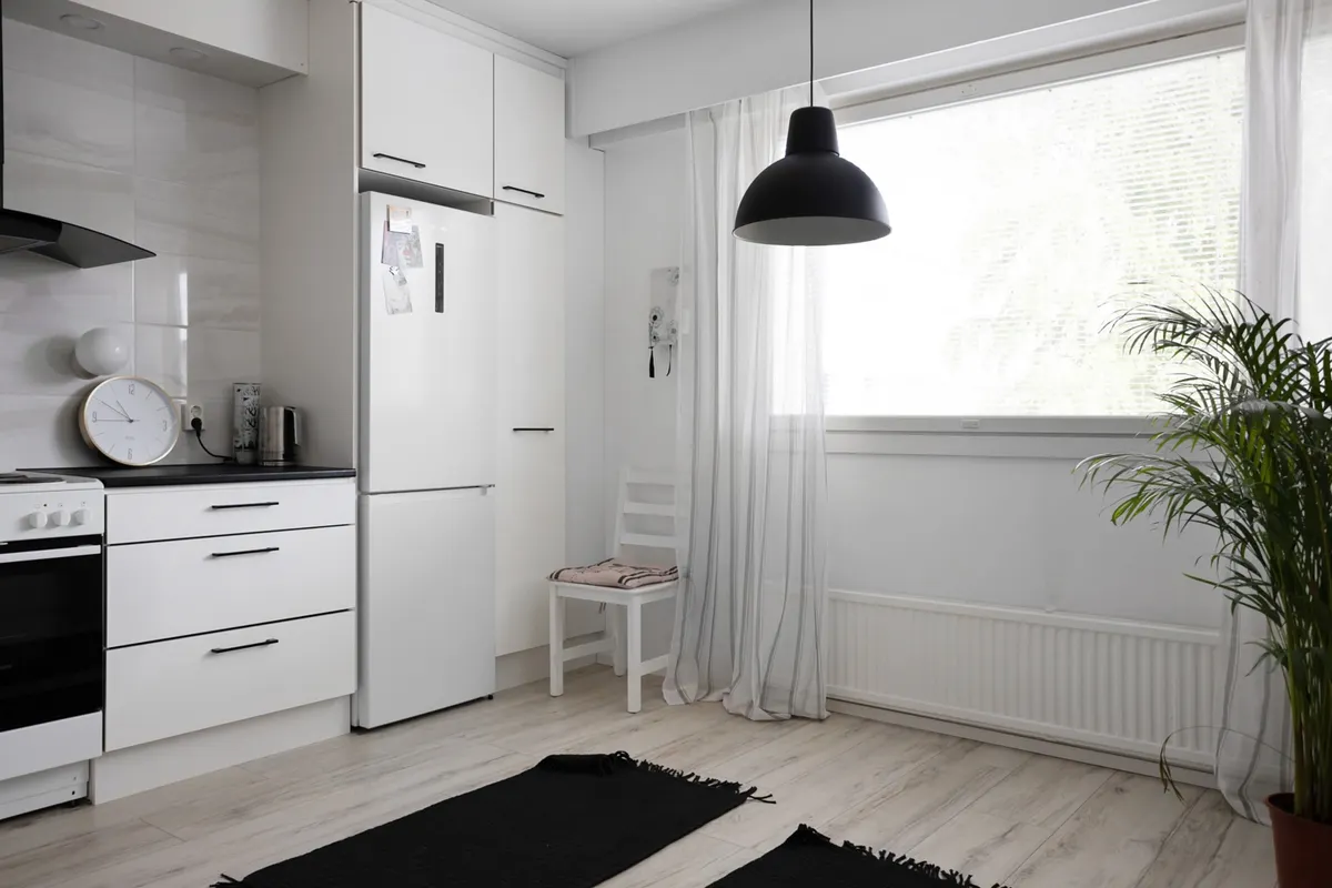 Cocina minimalista y luminosa con muebles blancos, gran ventana y decoración moderna