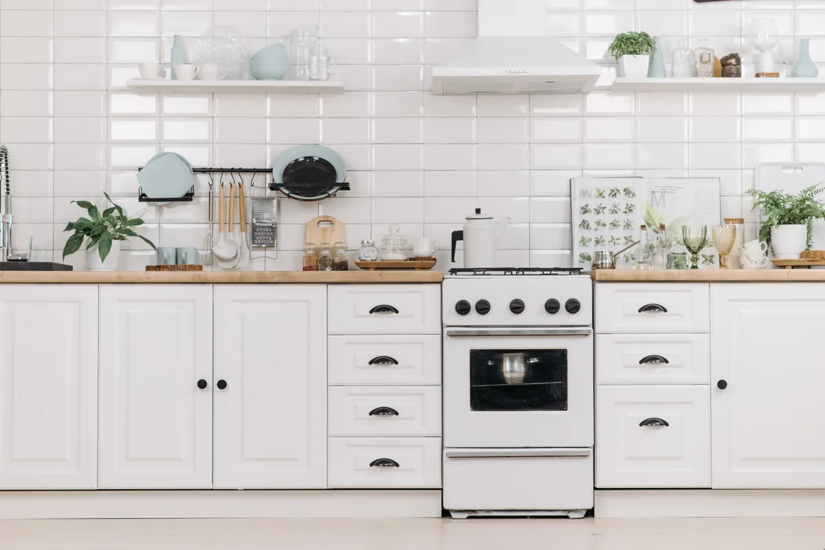 Cocina minimalista y luminosa con muebles blancos y fogones, limpia y ordenada