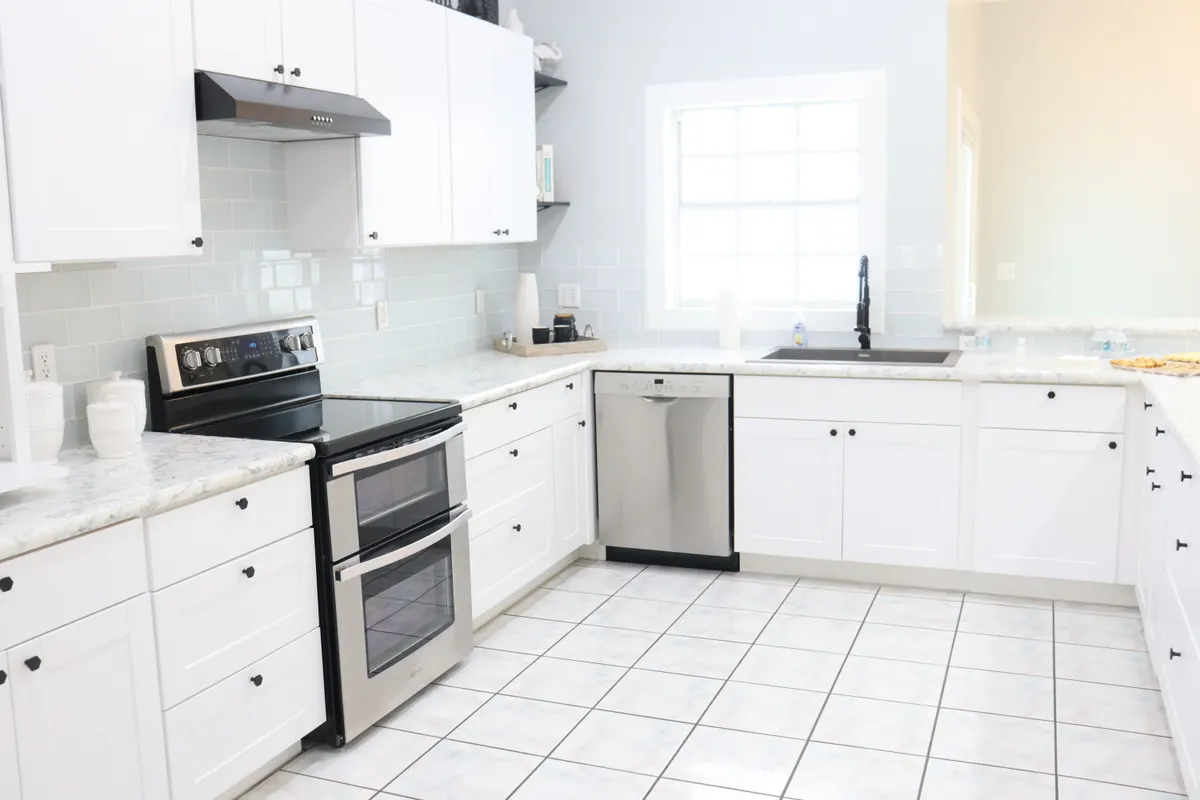 Cocina moderna, amplia y luminosa con muebles blancos, electrodomésticos y luz natural