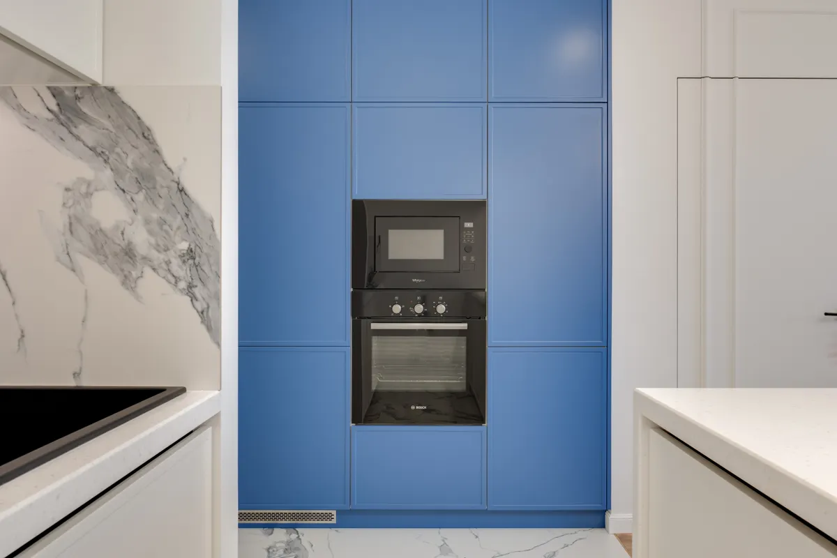 Cocina moderna con muebles azules, horno empotrado y microondas