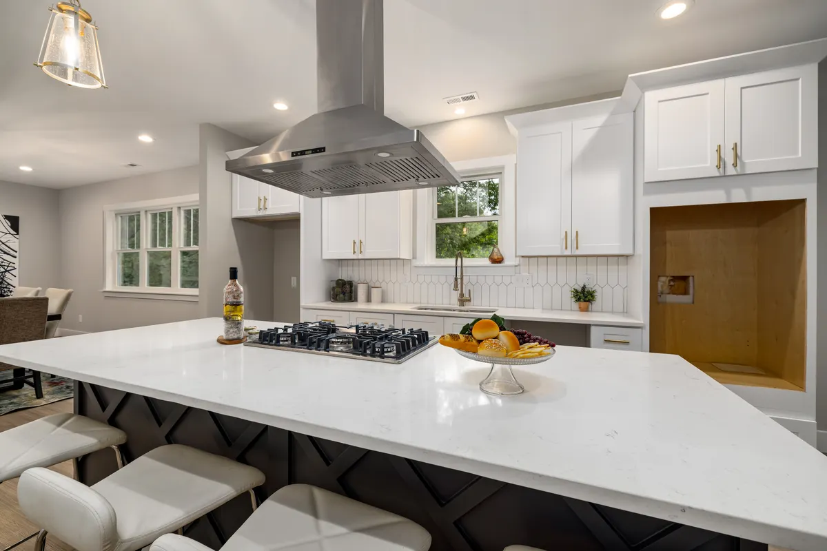 Cocina moderna con muebles blancos, isla y campana extractora de acero inoxidable