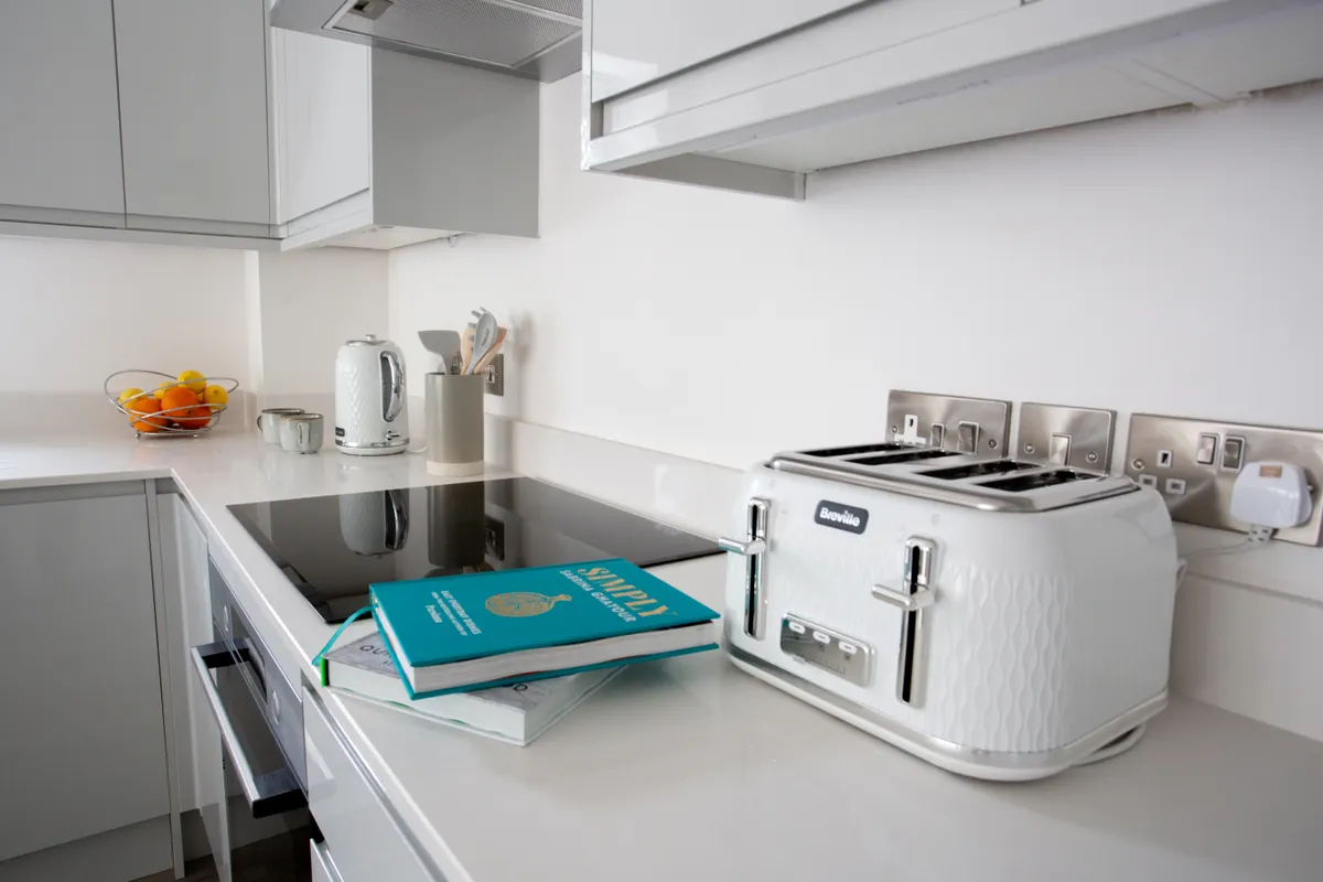 Cocina moderna con una tostadora blanca y una placa de inducción