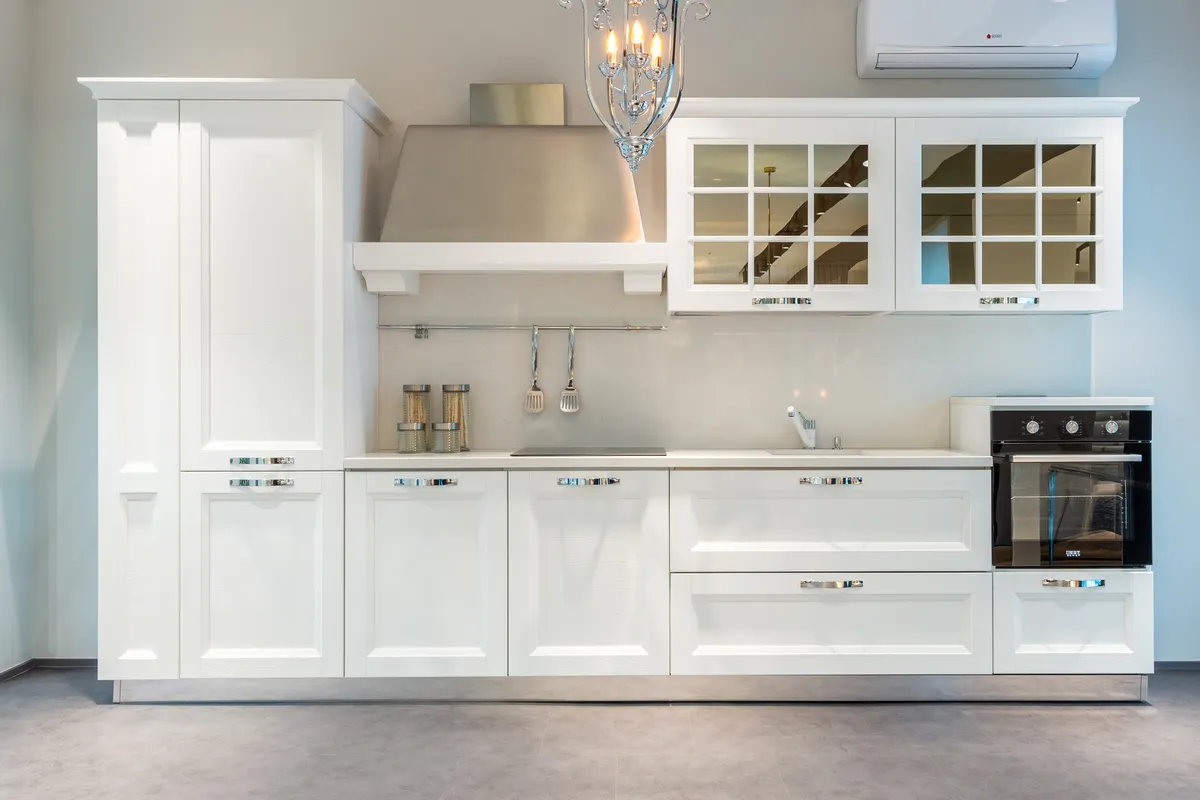 Cocina moderna y amueblada con armarios blancos y electrodomésticos actuales en un piso amplio