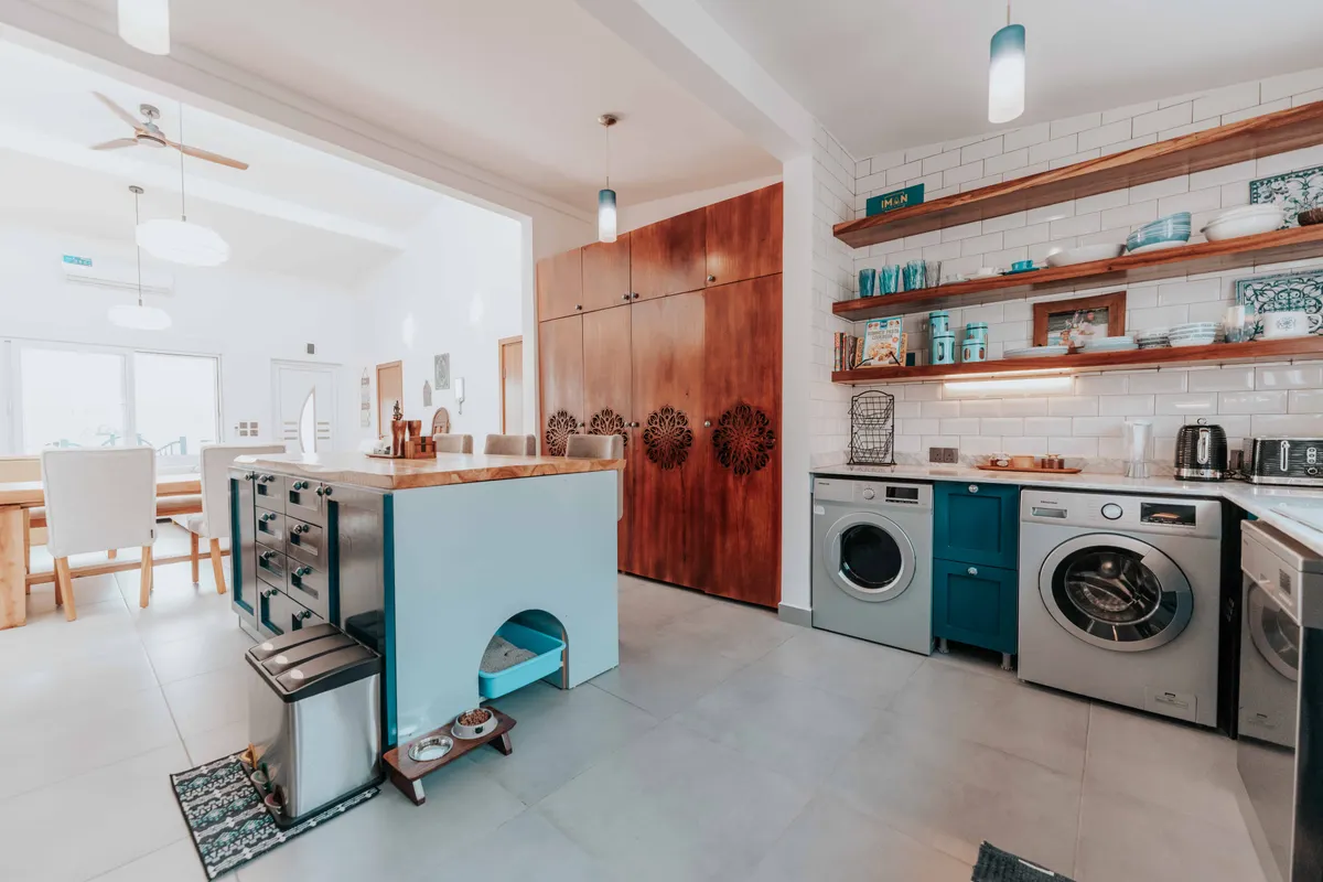 Cocina moderna y luminosa con zona de comedor, estantes abiertos y electrodomésticos de diseño