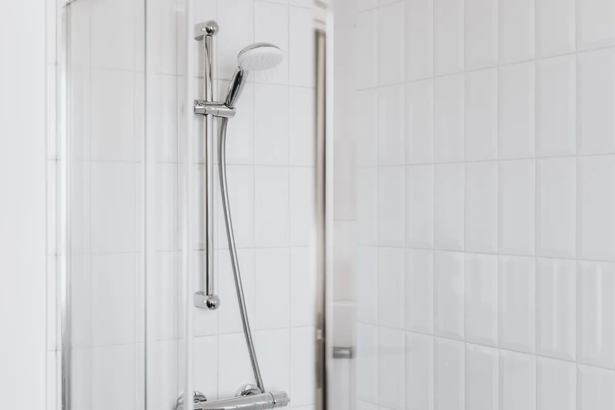 Conjunto de ducha con grifería cromada y azulejos blancos