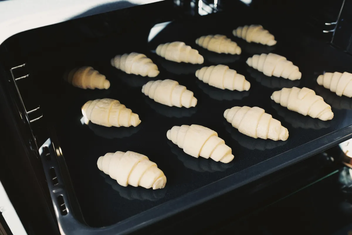Cruasanes aún crudos horneándose en una bandeja dentro del horno