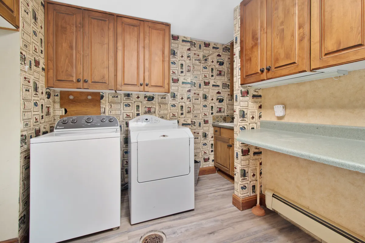 Cuarto de lavado acogedor con muebles de madera, lavadora y secadora