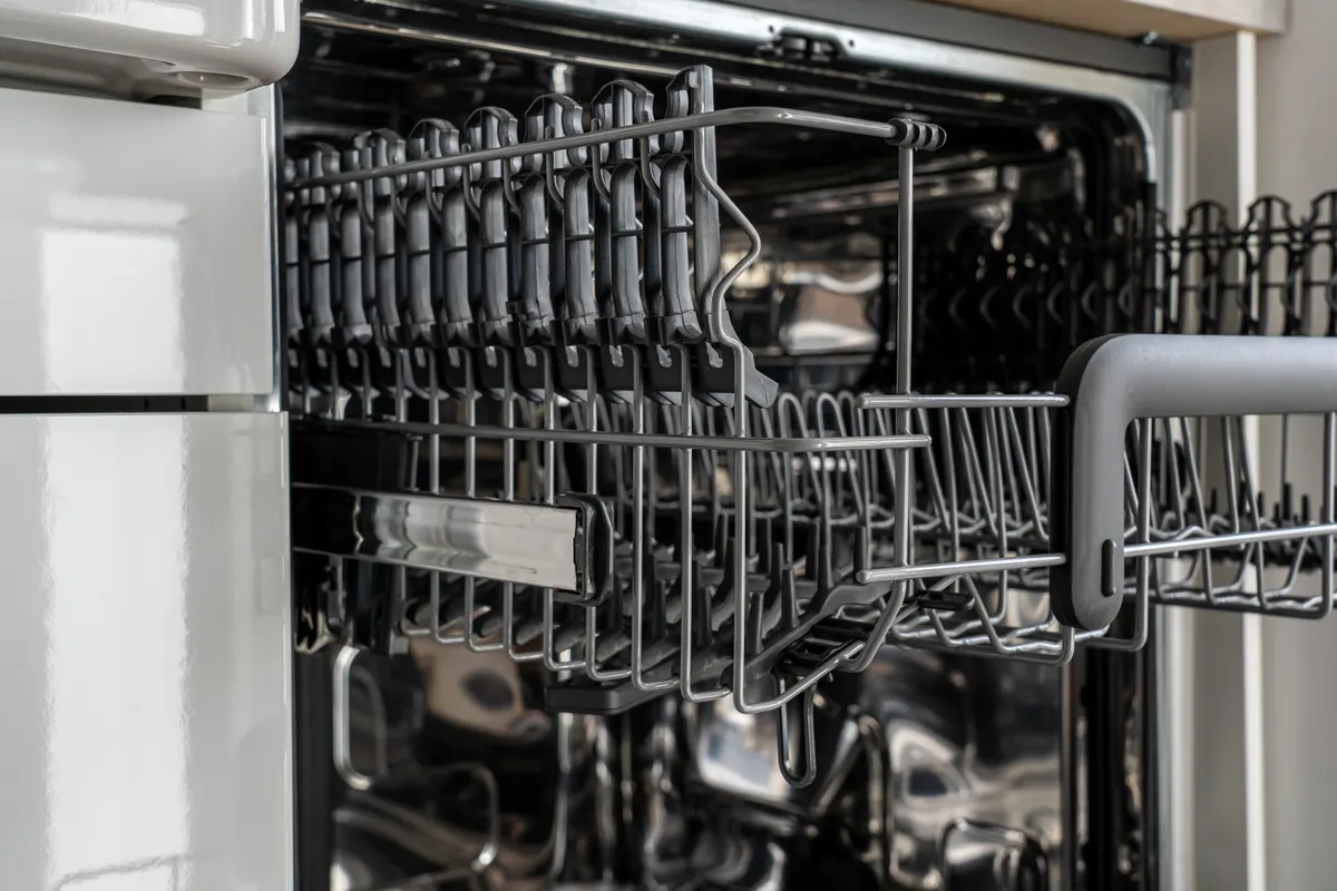 Detalle de la cesta vacía de un lavavajillas moderno de acero inoxidable