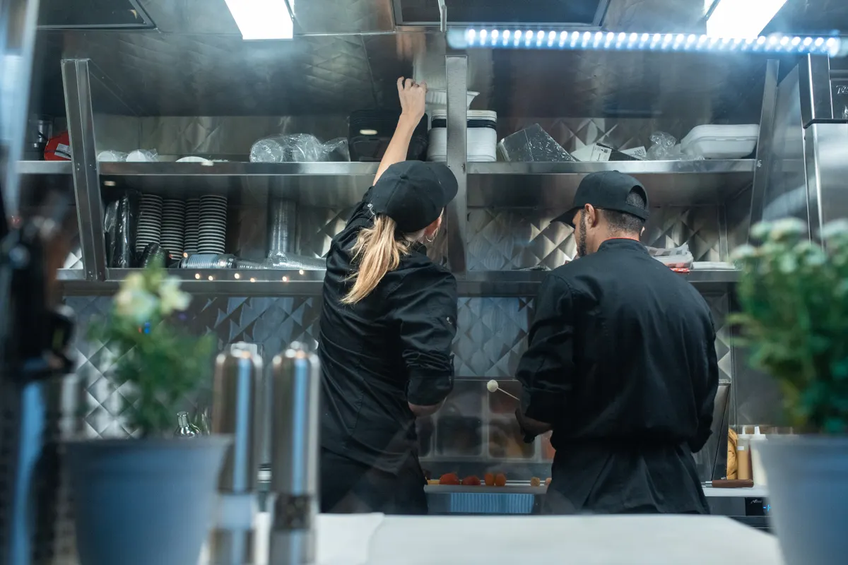 Dos cocineros preparando comida en una cocina profesional