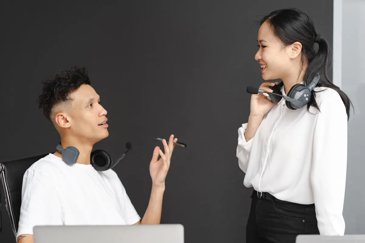 Dos compañeros con auriculares charlando en una oficina moderna