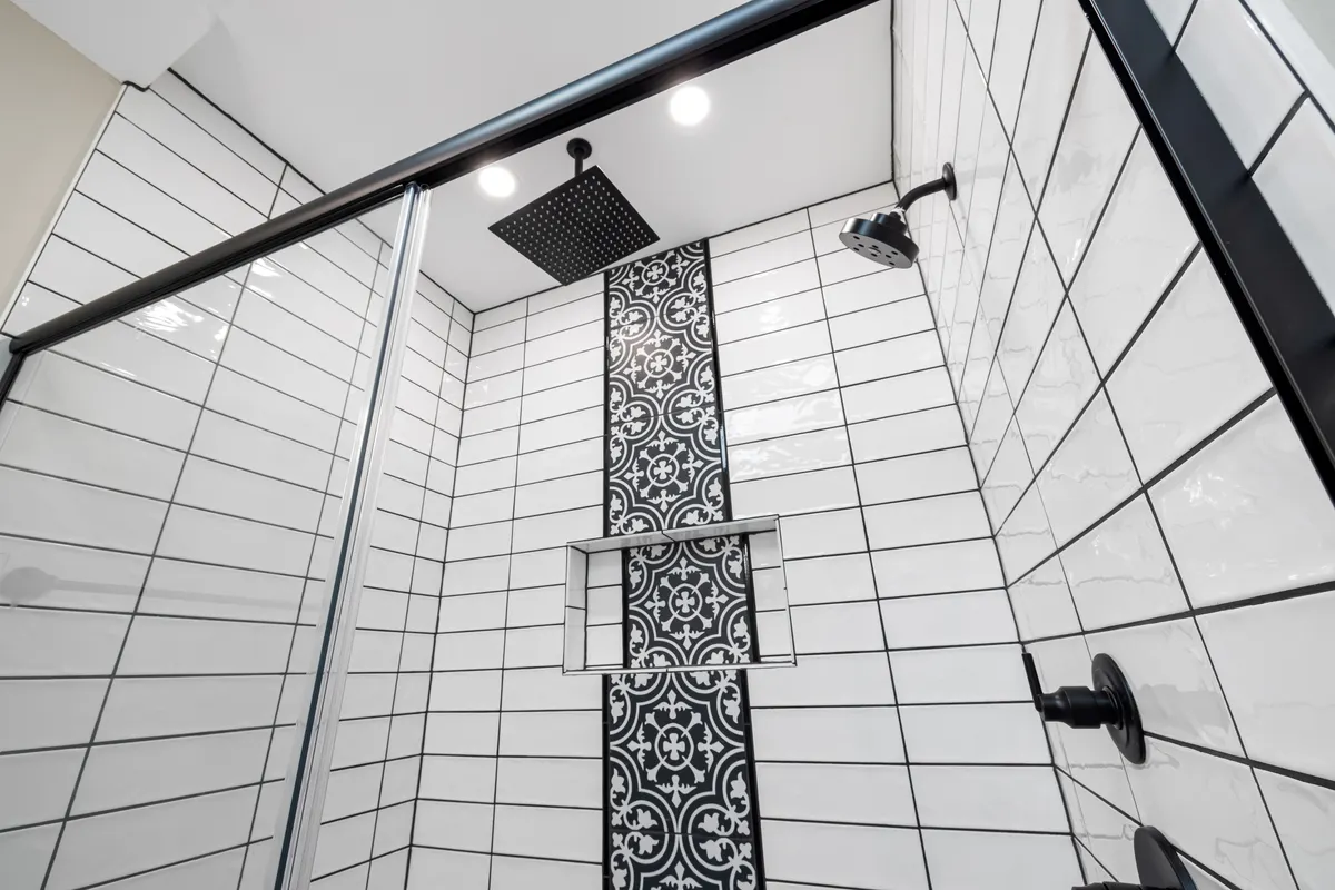 Ducha moderna con pared de azulejo estampado y grifería negra