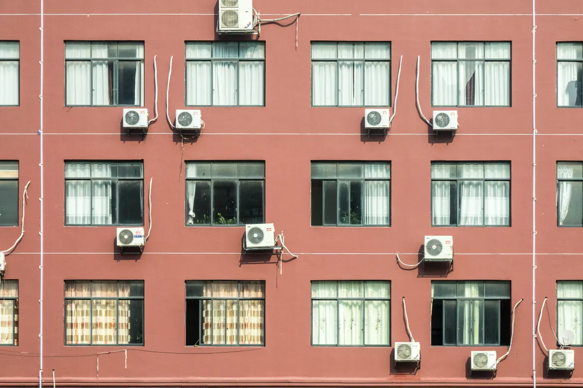 Edificio rojo con numerosas ventanas y aparatos de aire acondicionado en la fachada