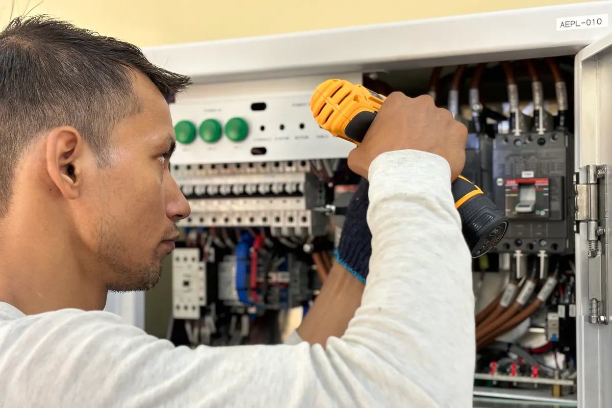 Electricista usando un taladro en un cuadro eléctrico de interior