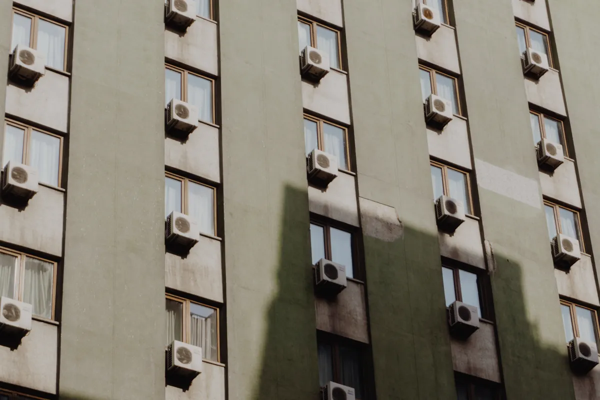 Fachada de un bloque de pisos urbano con un aparato de aire acondicionado en cada ventana
