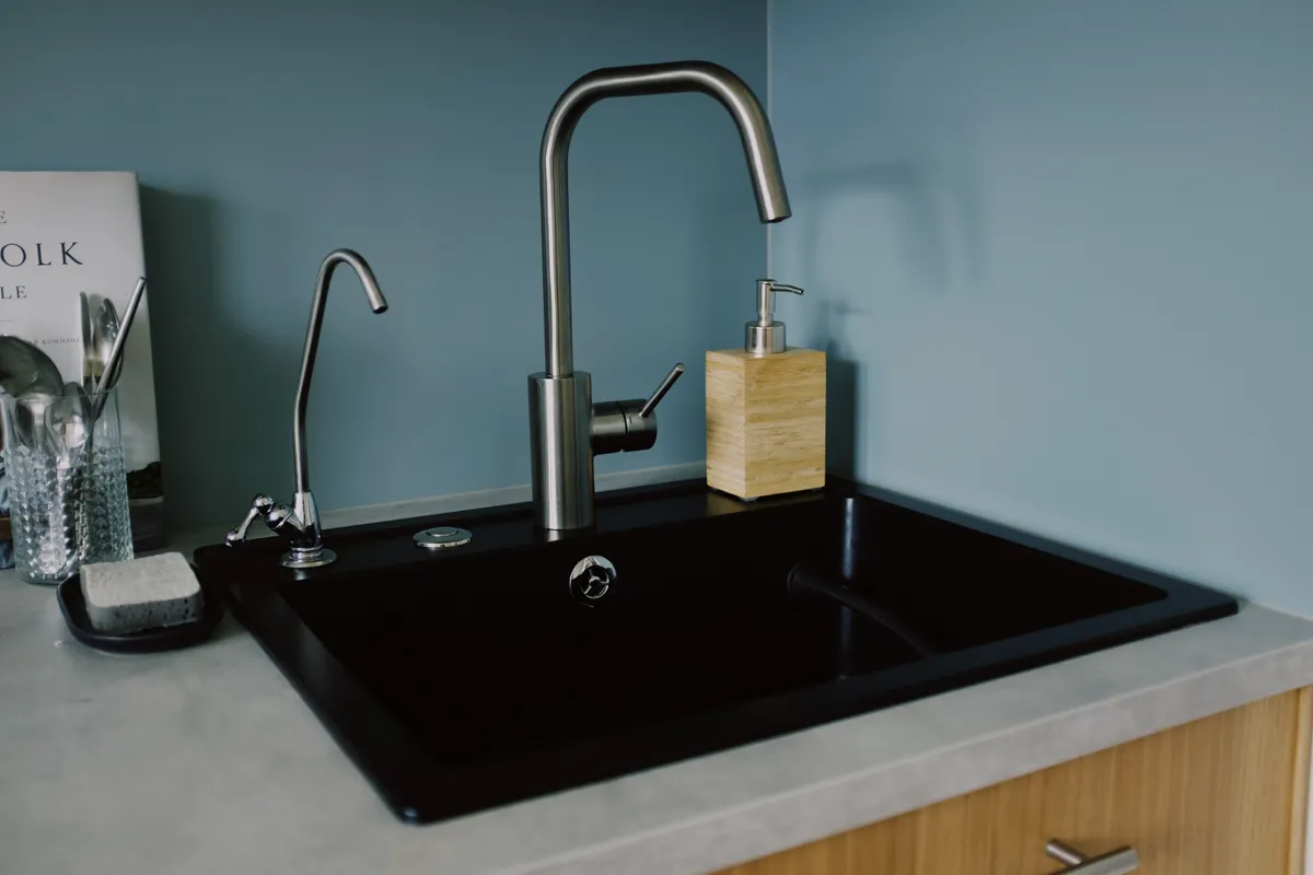 Fregadero de cocina con grifo y dispensador de jabón en un ambiente minimalista