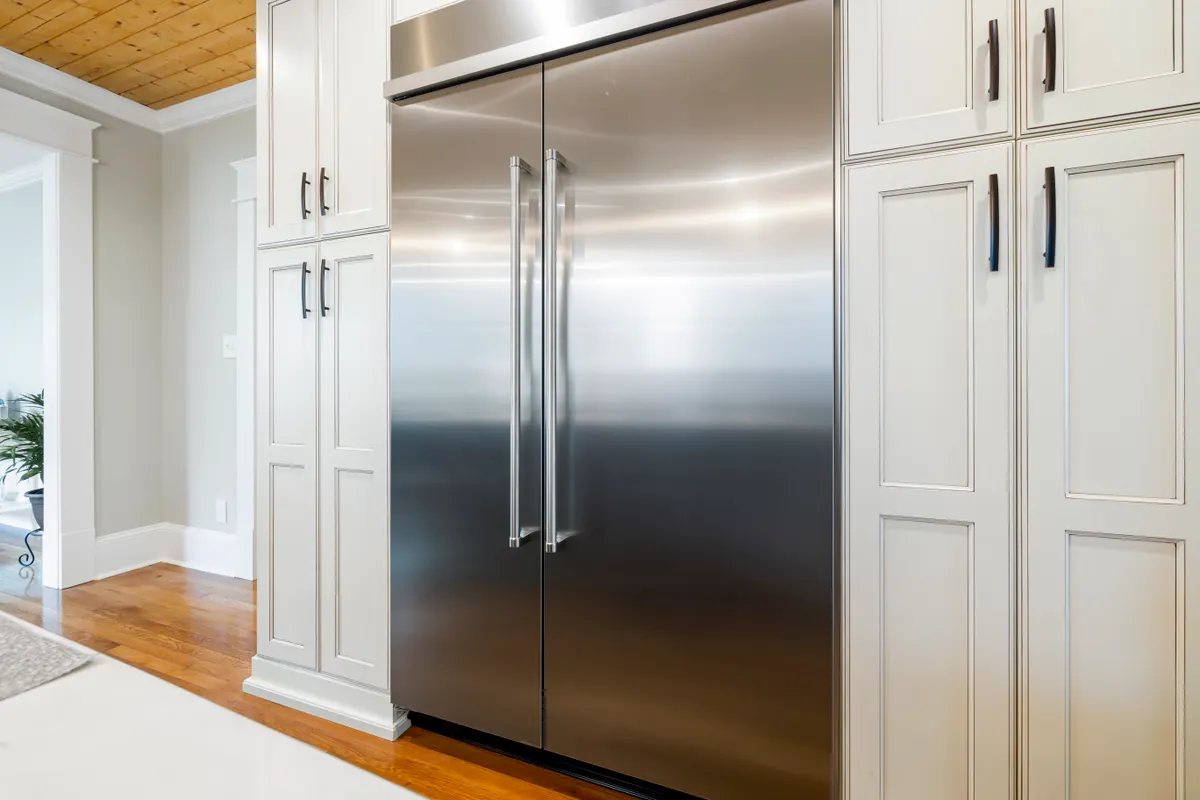 Frigorífico de acero inoxidable entre muebles elegantes en una cocina luminosa