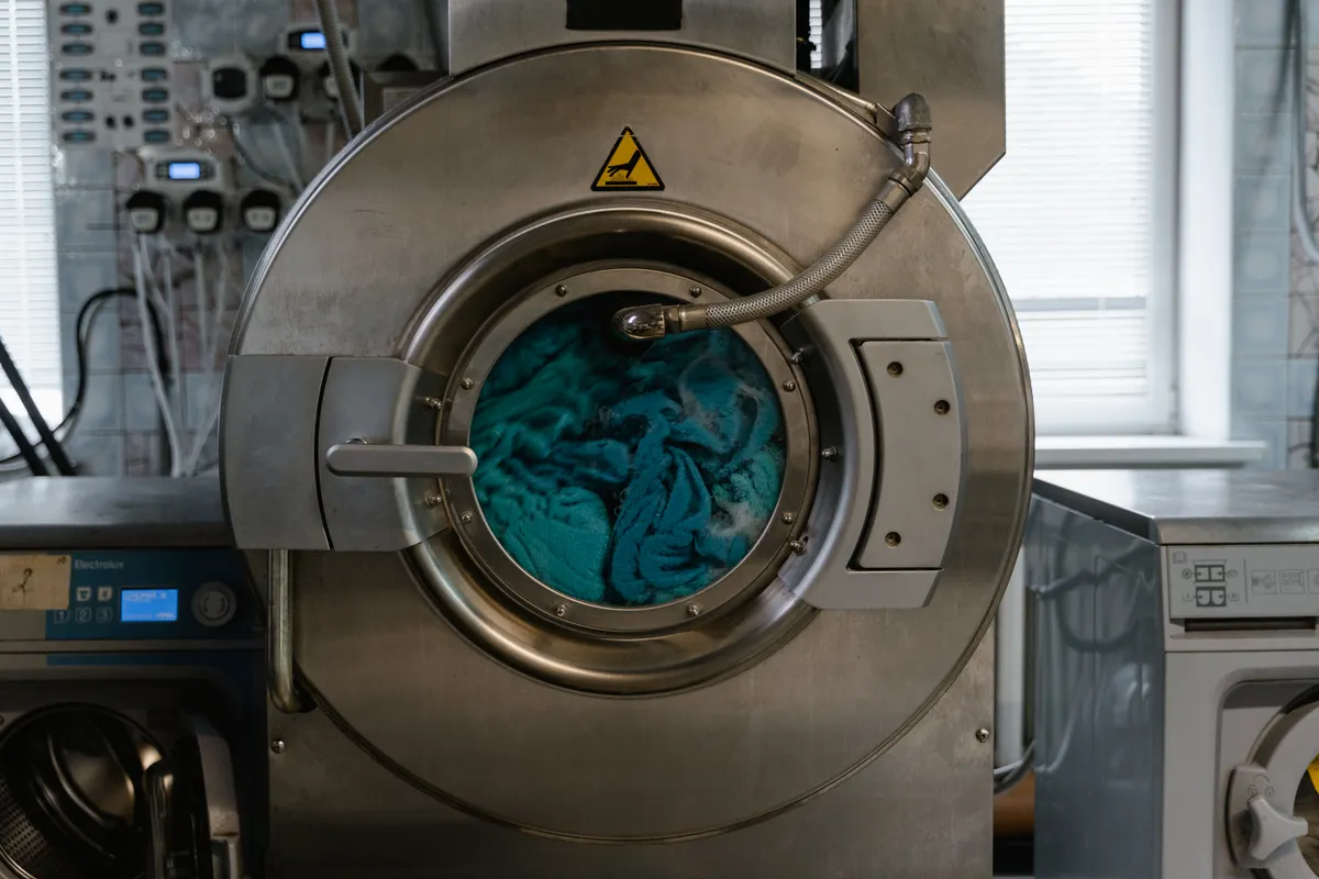Gran lavadora industrial con tejidos azules en una lavandería