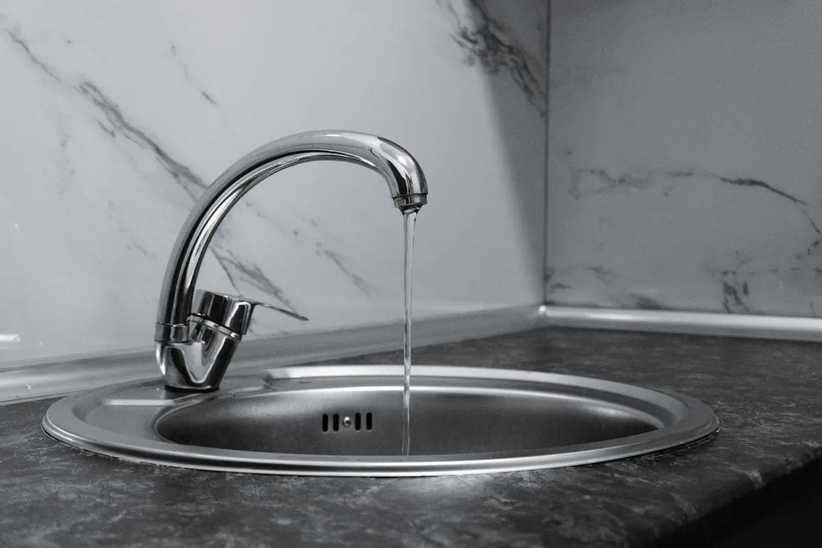 Grifo cromado con el agua corriendo en una cocina moderna con encimera de mármol