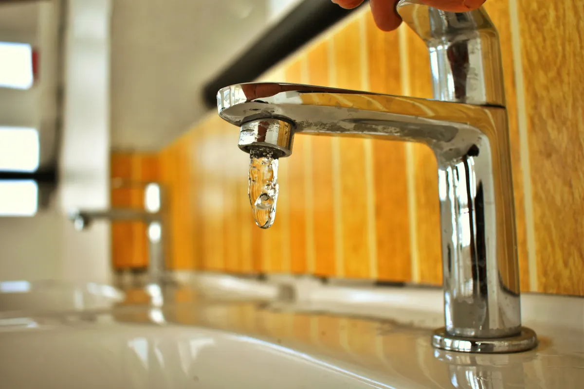 Grifo cromado de diseño estilizado con una gota de agua, en primer plano