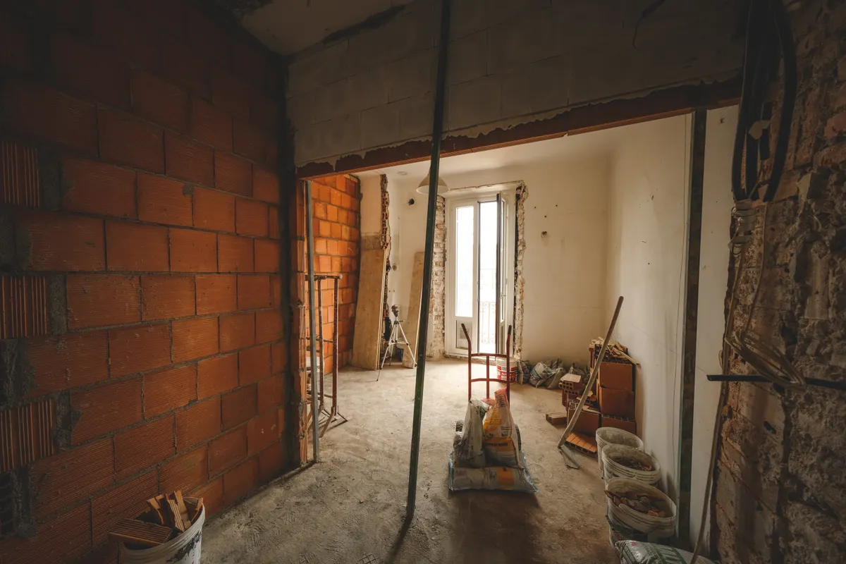 Habitación a medio reformar con paredes de ladrillo visto y materiales de obra