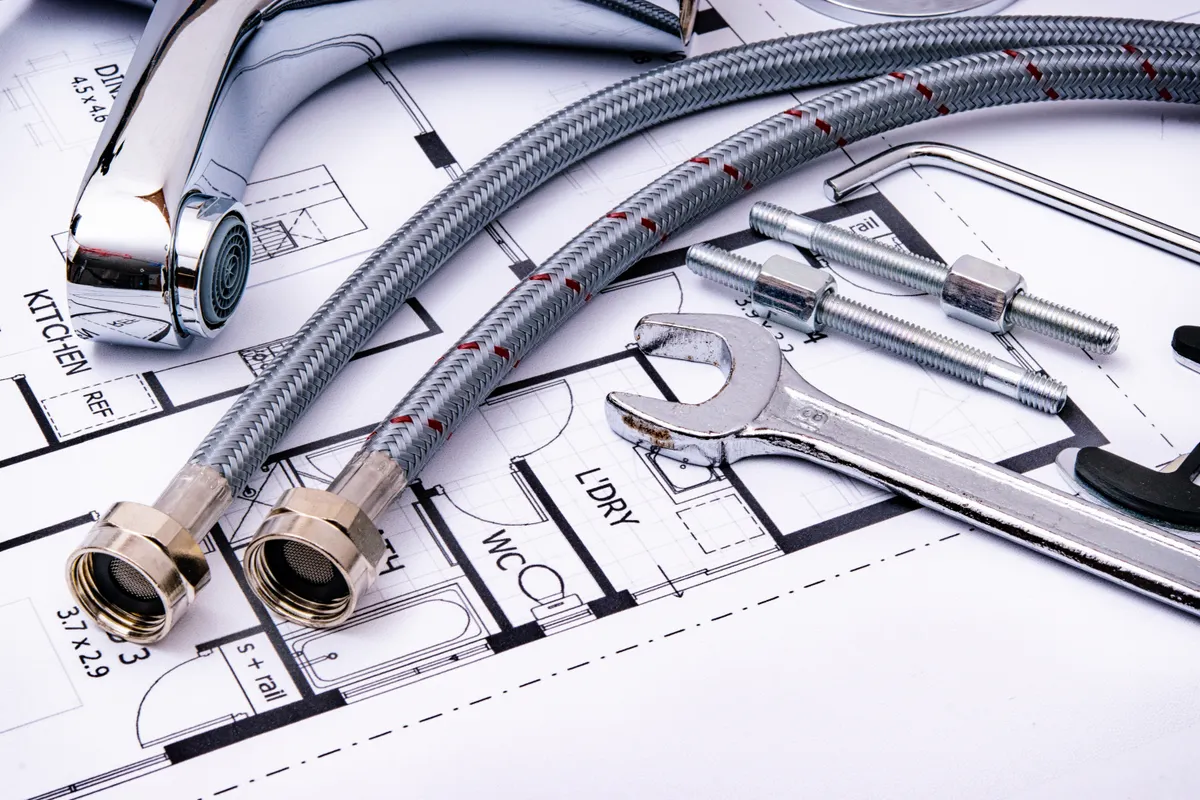 Herramientas de fontanería y un grifo sobre un plano arquitectónico