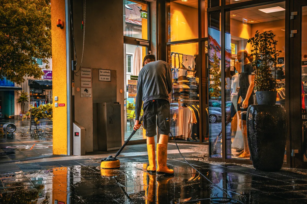 Hombre limpiando la entrada de una tienda en un día de lluvia